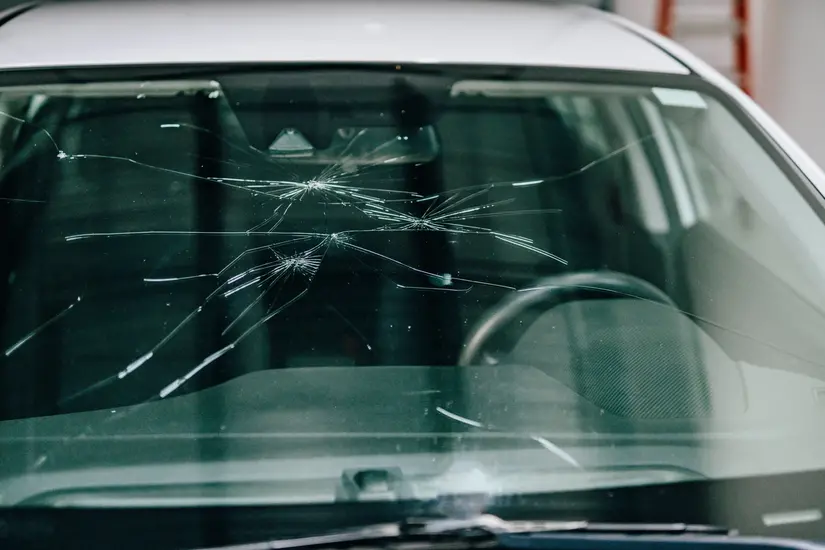 Car windshield with large cracks spread across front window.
